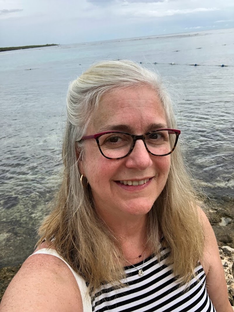 Dr. Tana Allen, Memorial University’s representative in the ORCA Council. She is wearing glasses and smiling at the picture with the ocean as background.