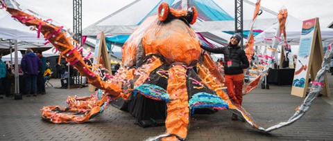 Large orange octopus art piece with a person standing next to it.
