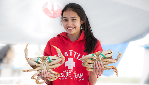 A girl holding a crab in each hand.