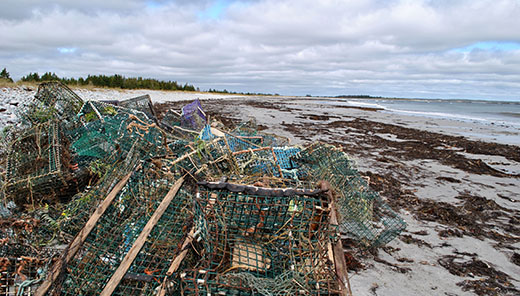lobster traps piled up on a beach.