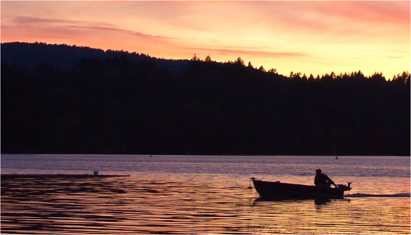 A person in a small fishing boat at sunset